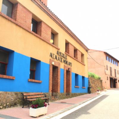 Entrada del albergue con pared azul y ocre y logotipo