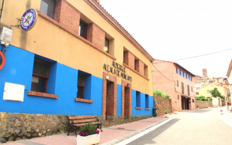 Entrada del albergue con pared azul y ocre y logotipo